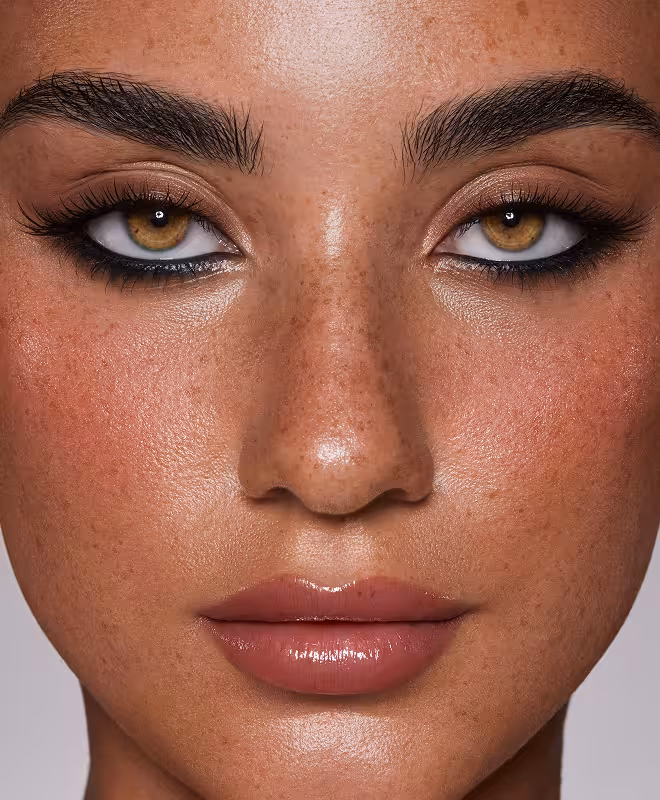 Schönheitsaufnahme eines Gesichts mit betonten Augen, vollem Wimpernlook und glänzendem Lippenstift.