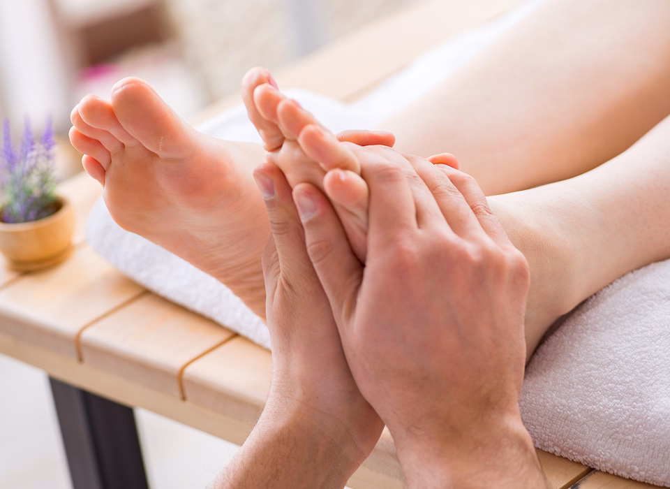 Füße werden sanft massiert, angenehme Entspannung auf einem Behandlungstisch in einem Wellnessbereich.