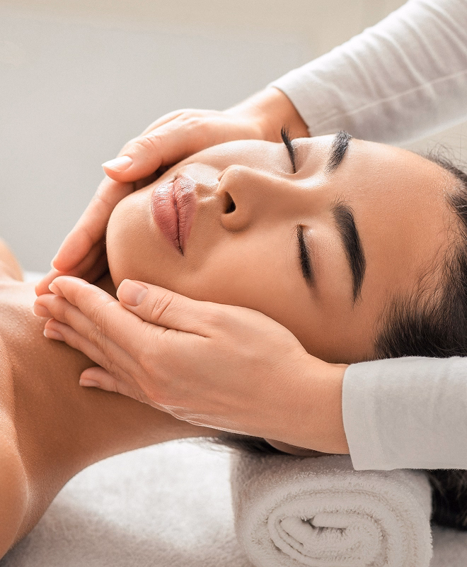 Frau erhält eine entspannende Gesichtsbehandlung mit sanften Massagen in einem Wellnessbereich.