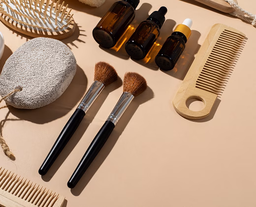 Schönheitsaccessoires: zwei Makeup-Pinsel, Flaschen und Kämme auf einem beigen Hintergrund.