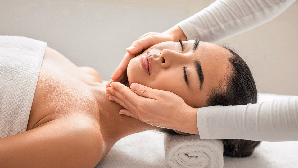 Frau erhält Gesichtsmassage in einem Spa, entspannt mit geschlossenen Augen.